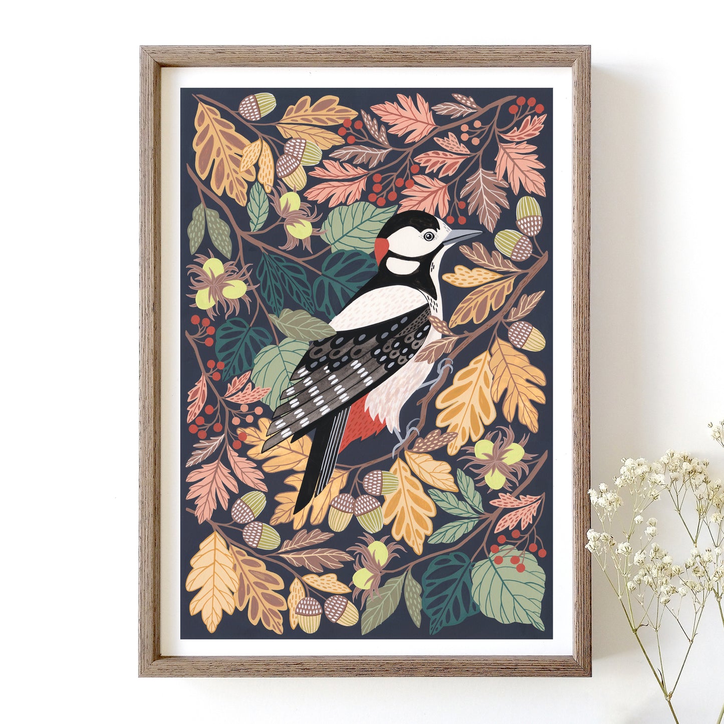 Framed artwork of a woodpecker among autumn leaves on a white wall.