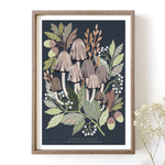 An art print featuring a cluster of common inkcap mushrooms with surrounding green leaves and dark background in a wooden frame.