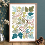 A framed botanical art print featuring gooseberries, leaves and flowers in greens, teal and olive tones.