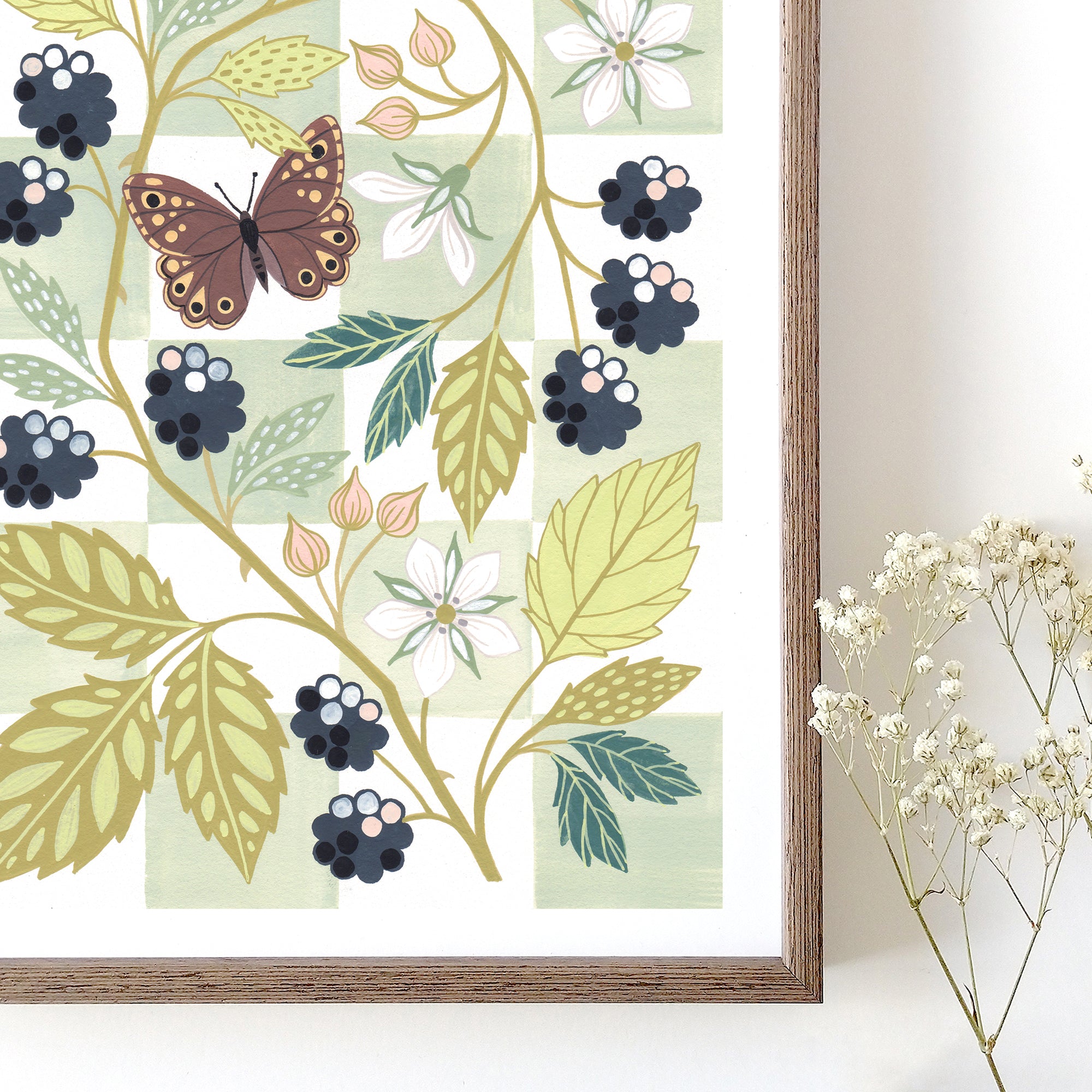 Framed botanical art print featuring a butterfly, leaves, flowers, and blackberries.