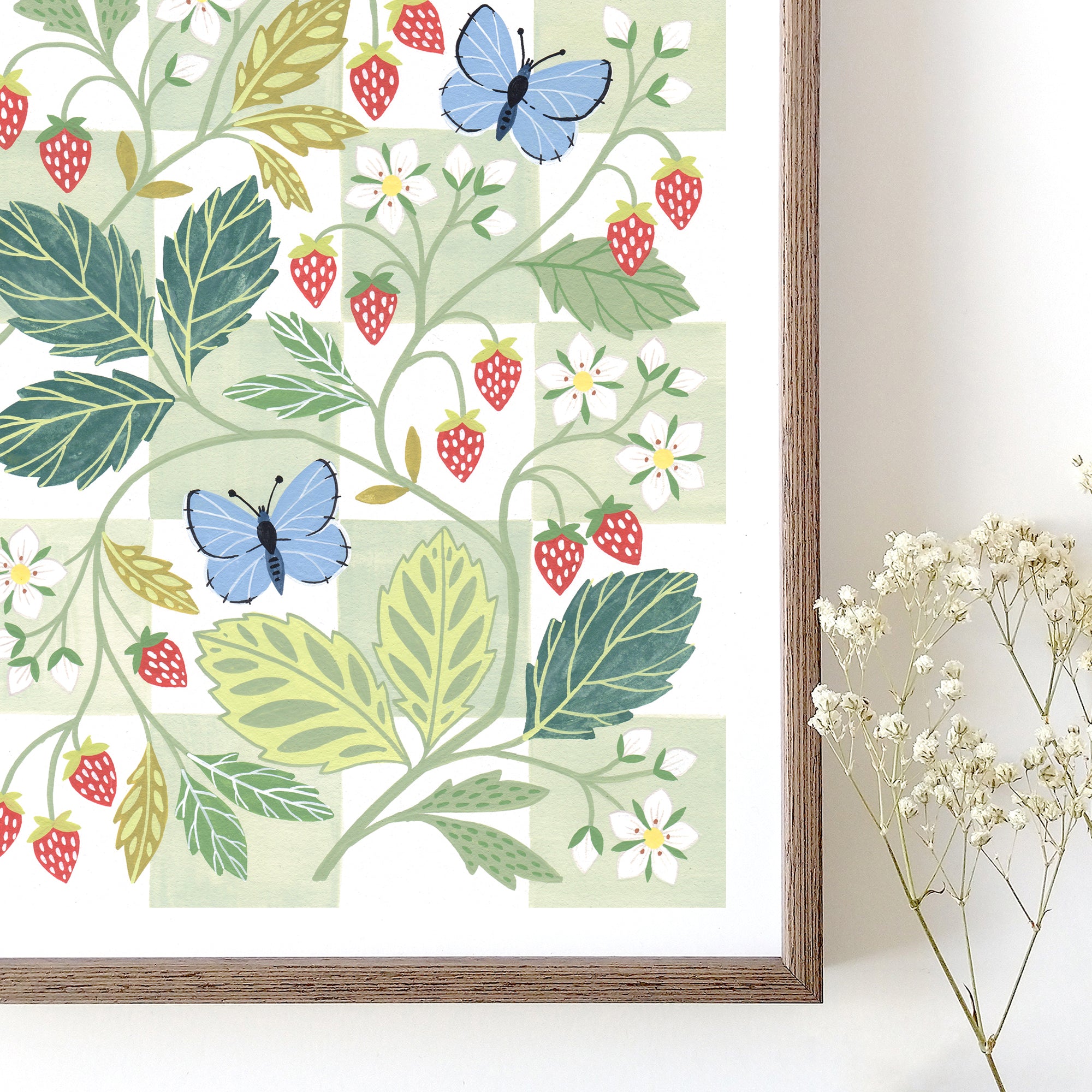Framed botanical wall art print with strawberries and blue butterflies against a white and green chequerboard background.