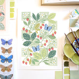A botanical painting of wild strawberries and common blue butterflies with paint palette and paint brushes.