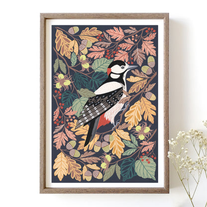 Framed artwork of a woodpecker among autumn leaves on a white wall.